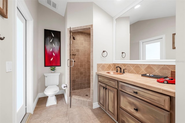 bathroom with an enclosed shower, vanity, vaulted ceiling, tile patterned flooring, and toilet