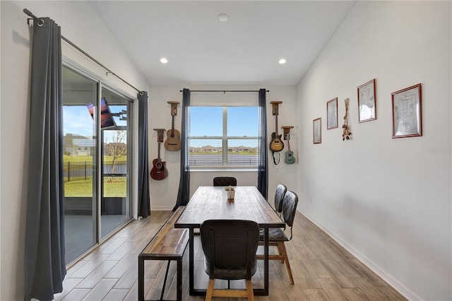 dining room featuring light wood-type flooring and vaulted ceiling