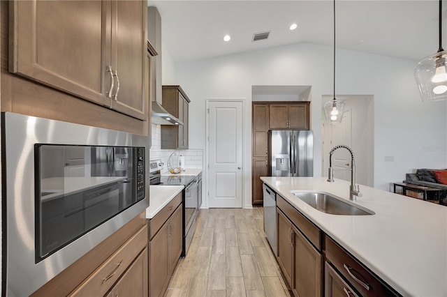 kitchen featuring sink, stainless steel appliances, light hardwood / wood-style flooring, pendant lighting, and lofted ceiling