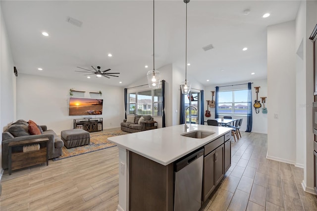 kitchen featuring sink, stainless steel dishwasher, light hardwood / wood-style floors, vaulted ceiling, and a kitchen island with sink