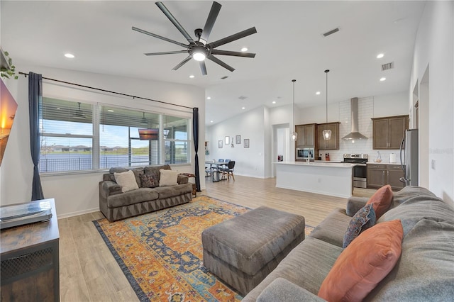 living room featuring ceiling fan, light wood-type flooring, and lofted ceiling