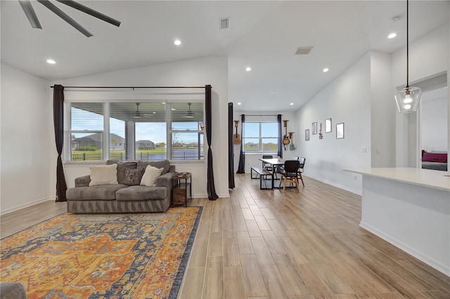 living room with ceiling fan, light hardwood / wood-style floors, and vaulted ceiling