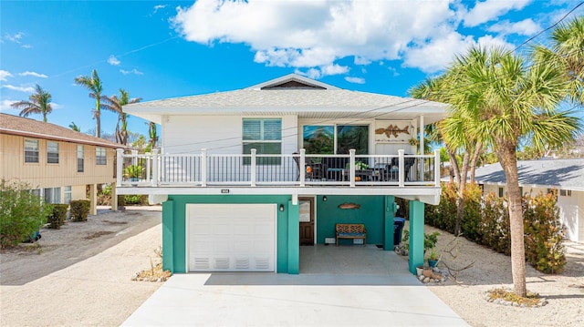 raised beach house with covered porch and a garage