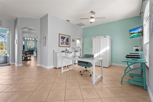 office with visible vents, baseboards, arched walkways, light tile patterned flooring, and a ceiling fan