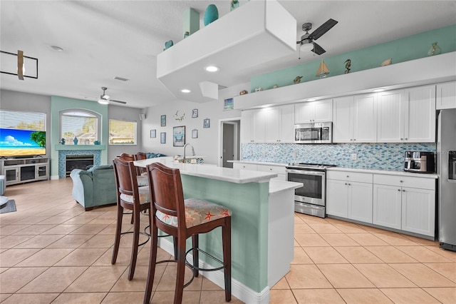 kitchen featuring stainless steel appliances, light tile patterned flooring, a ceiling fan, and light countertops