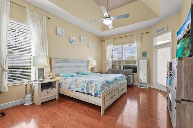 bedroom with access to exterior, baseboards, a raised ceiling, a ceiling fan, and wood-type flooring