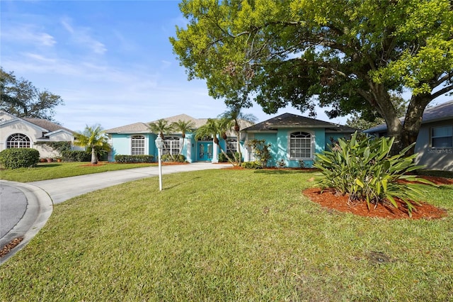 view of front of house featuring stucco siding, driveway, and a front yard