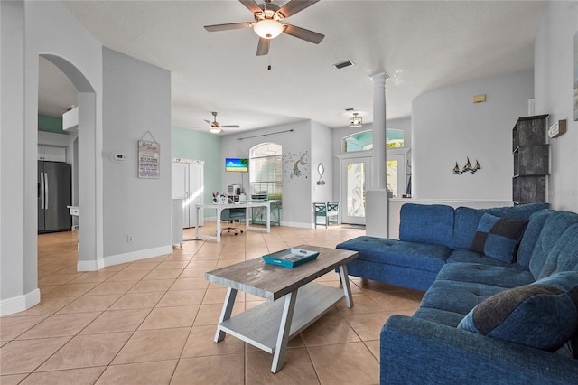 living room featuring light tile patterned floors, baseboards, visible vents, and decorative columns