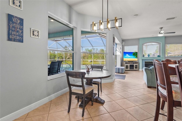 tiled dining area with a ceiling fan, baseboards, visible vents, a fireplace, and a sunroom