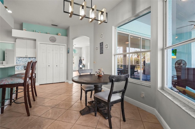 dining room with light tile patterned floors, visible vents, arched walkways, and baseboards