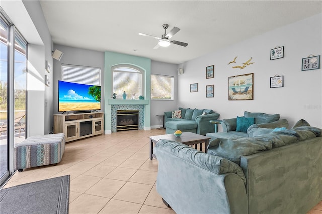 living room with light tile patterned floors, baseboards, ceiling fan, and a tile fireplace