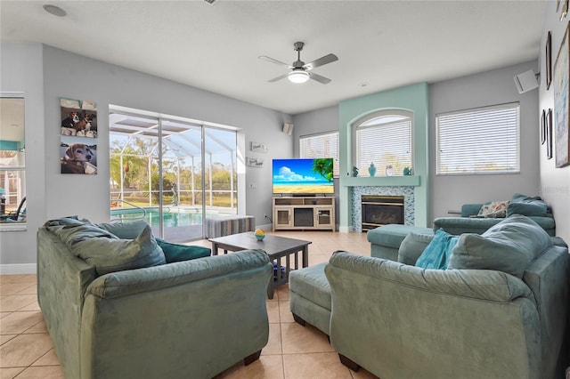 living area featuring light tile patterned floors, a ceiling fan, baseboards, a fireplace, and a sunroom