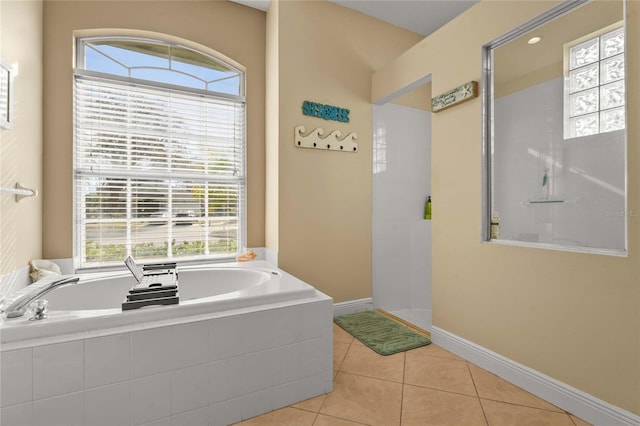 bathroom featuring a garden tub, a walk in shower, baseboards, and tile patterned floors