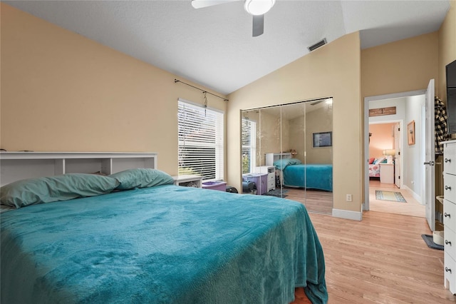 bedroom with visible vents, light wood finished floors, lofted ceiling, ceiling fan, and a closet