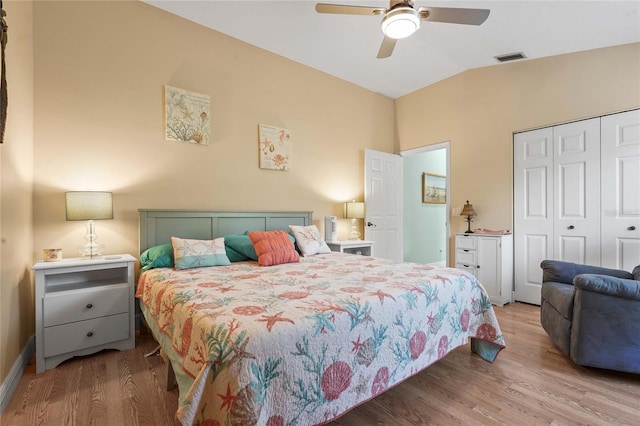 bedroom featuring a closet, visible vents, wood finished floors, and vaulted ceiling