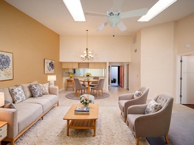 living room with ceiling fan with notable chandelier, light colored carpet, and high vaulted ceiling