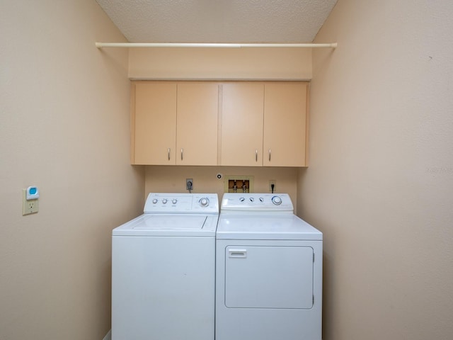 laundry area featuring washer and dryer, cabinets, and a textured ceiling