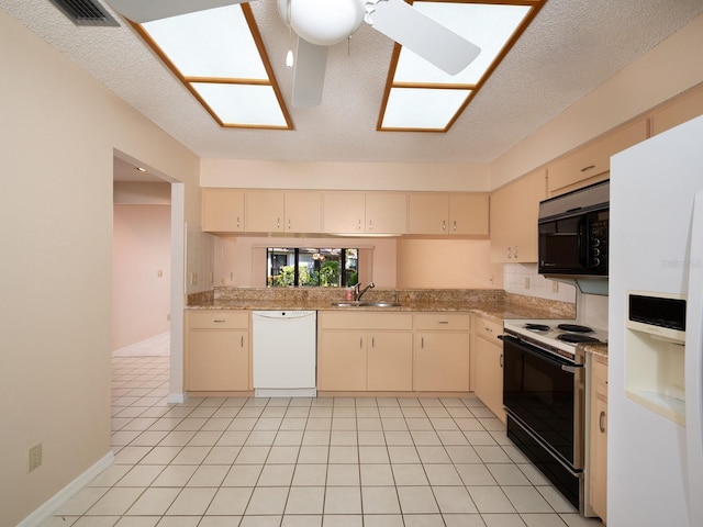 kitchen featuring a skylight, cream cabinets, white appliances, and sink