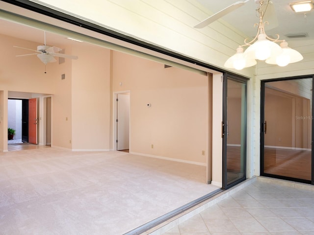 unfurnished room featuring a towering ceiling, light colored carpet, and ceiling fan with notable chandelier