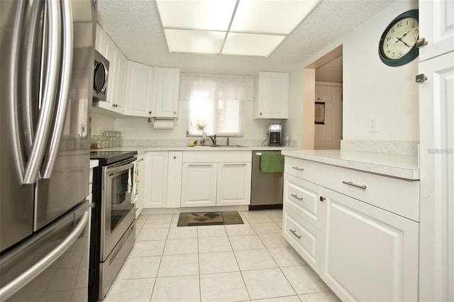 kitchen with sink, white cabinets, stainless steel appliances, and light tile patterned floors