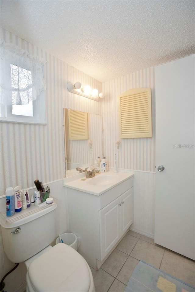 bathroom with vanity, a textured ceiling, tile patterned floors, and toilet