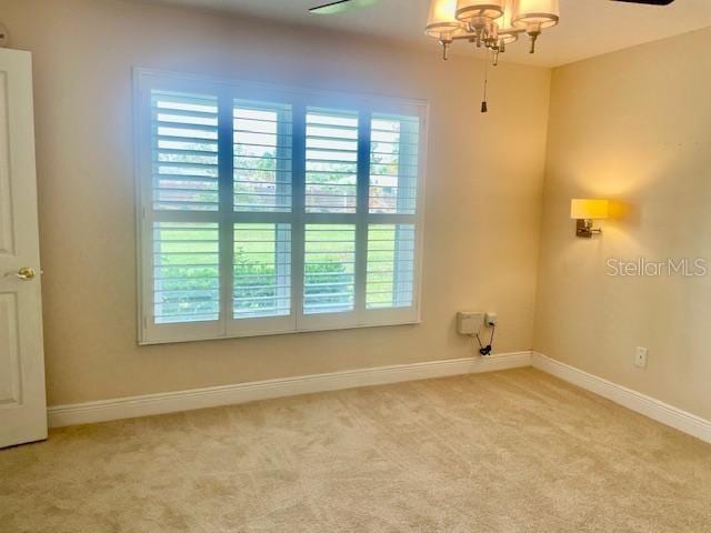 clothes washing area featuring ceiling fan with notable chandelier and light carpet