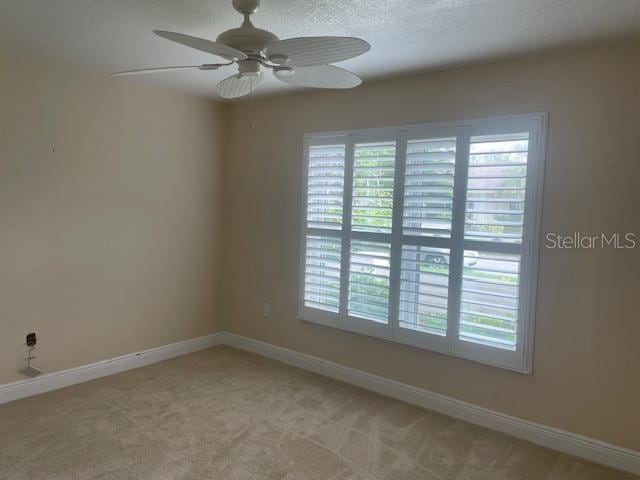 carpeted spare room featuring ceiling fan and a textured ceiling