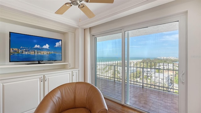 living area with a water view, crown molding, ceiling fan, and wood-type flooring