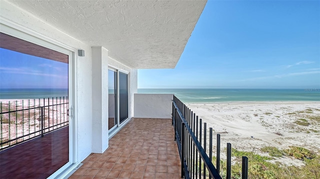 balcony featuring a water view and a beach view