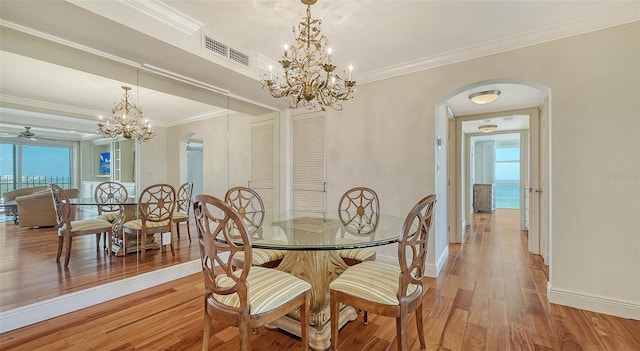 dining area with hardwood / wood-style floors, ceiling fan with notable chandelier, crown molding, and a wealth of natural light