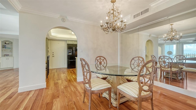 dining room featuring light wood-type flooring, ornamental molding, and a notable chandelier