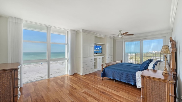 bedroom with access to outside, multiple windows, ceiling fan, and a water view