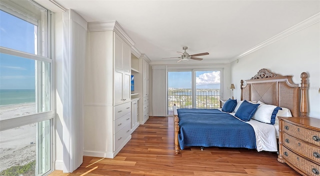 bedroom featuring hardwood / wood-style floors, a water view, ceiling fan, access to exterior, and ornamental molding