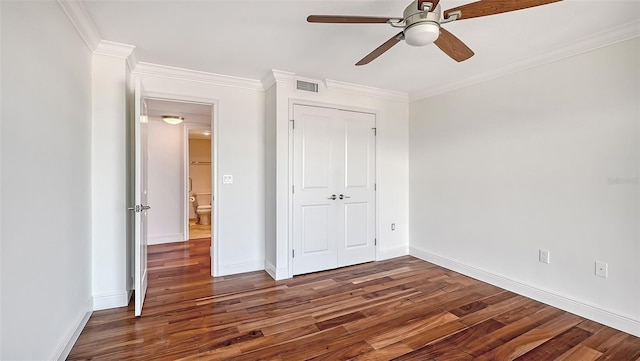 unfurnished bedroom featuring ceiling fan, crown molding, dark wood-type flooring, and a closet