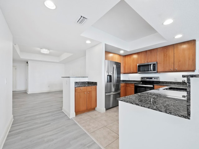 kitchen with sink, a raised ceiling, kitchen peninsula, and stainless steel appliances