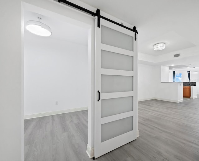 hallway with a barn door and light hardwood / wood-style flooring