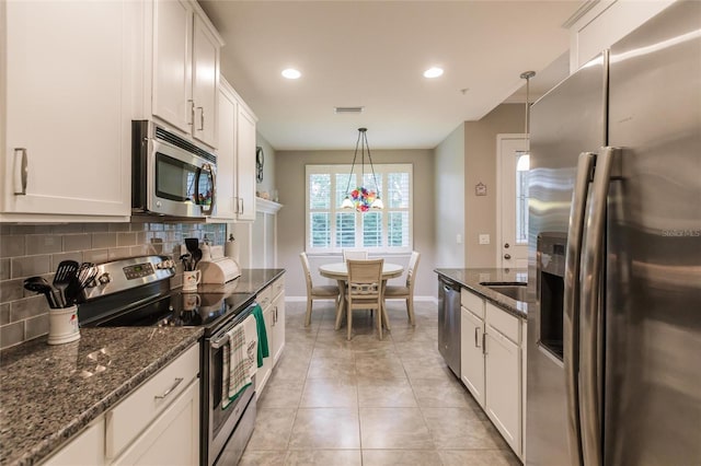 kitchen featuring decorative light fixtures, white cabinetry, appliances with stainless steel finishes, and dark stone counters