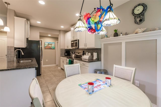 kitchen with decorative backsplash, white cabinets, stainless steel appliances, and decorative light fixtures