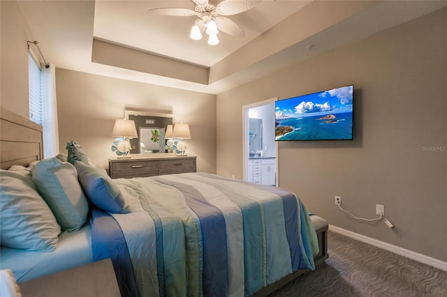 carpeted bedroom featuring ensuite bathroom, a raised ceiling, and ceiling fan