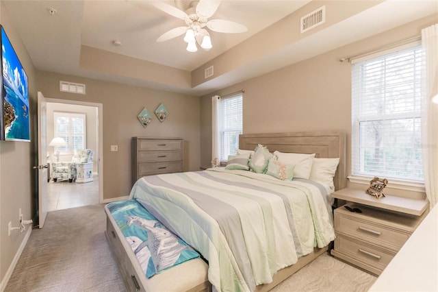 bedroom with multiple windows, ceiling fan, and light carpet