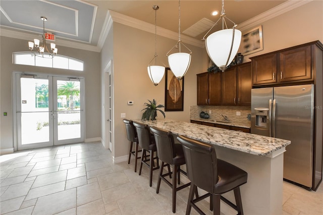 kitchen with light stone countertops, stainless steel refrigerator with ice dispenser, crown molding, pendant lighting, and decorative backsplash