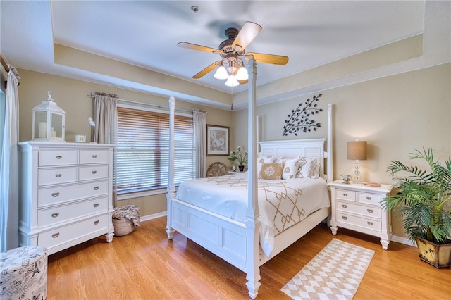 bedroom featuring ceiling fan, light hardwood / wood-style floors, and a raised ceiling