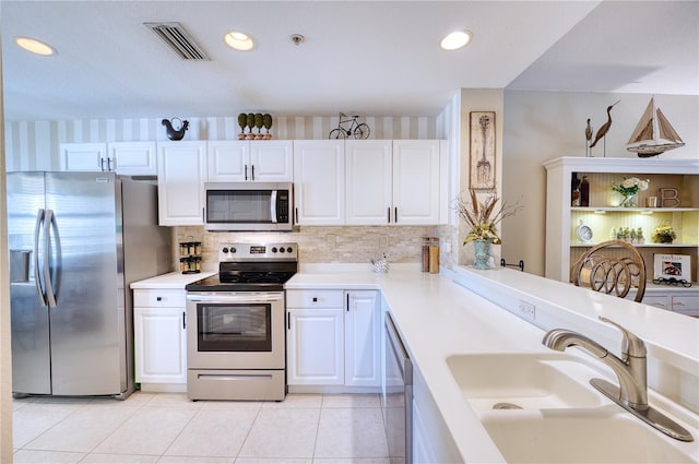 kitchen with sink, white cabinets, appliances with stainless steel finishes, and kitchen peninsula