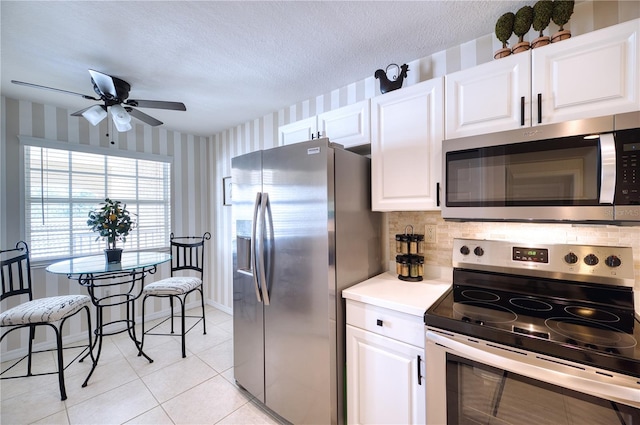 kitchen with ceiling fan, white cabinets, stainless steel appliances, and a textured ceiling