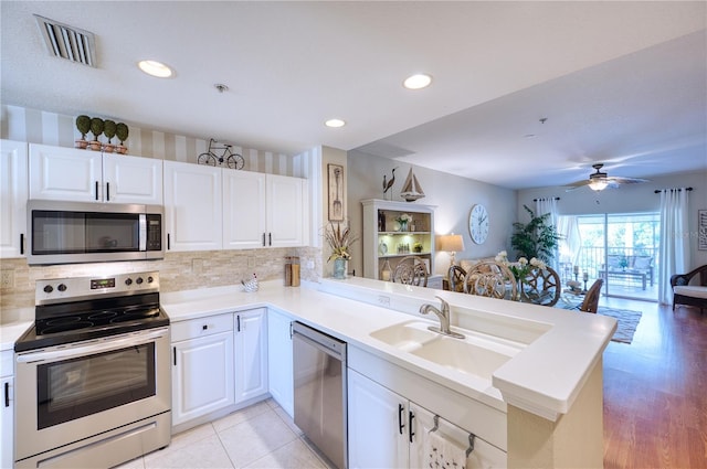 kitchen with appliances with stainless steel finishes, white cabinetry, tasteful backsplash, sink, and kitchen peninsula