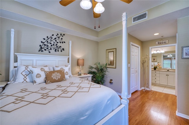 bedroom with ceiling fan, light hardwood / wood-style floors, ensuite bath, a closet, and ornate columns