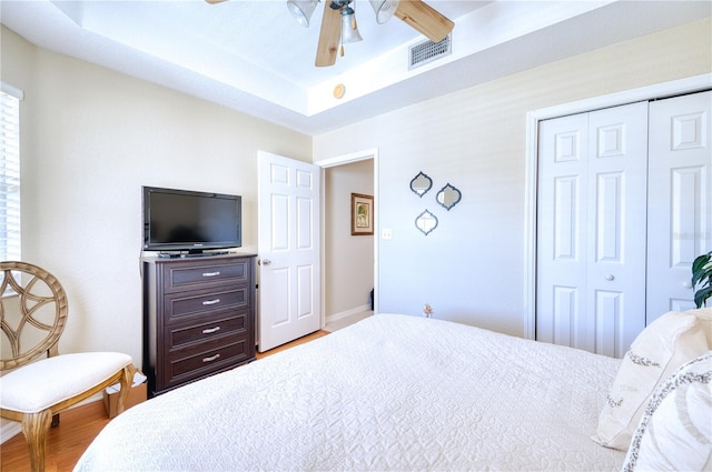 bedroom featuring ceiling fan, hardwood / wood-style floors, a closet, and a raised ceiling