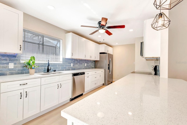 kitchen with decorative light fixtures, white cabinetry, sink, and stainless steel appliances