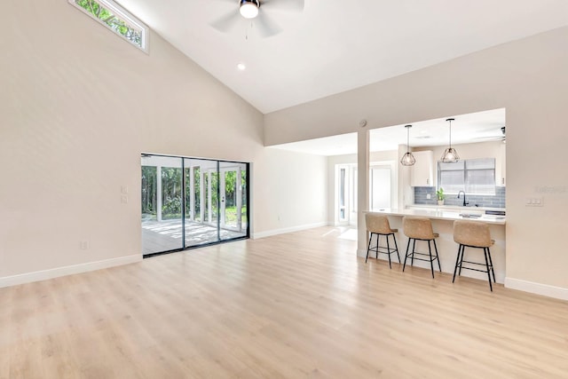 living room featuring plenty of natural light, ceiling fan, high vaulted ceiling, and light hardwood / wood-style flooring