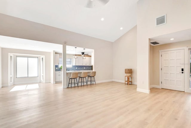 living room featuring light wood-type flooring, high vaulted ceiling, and ceiling fan